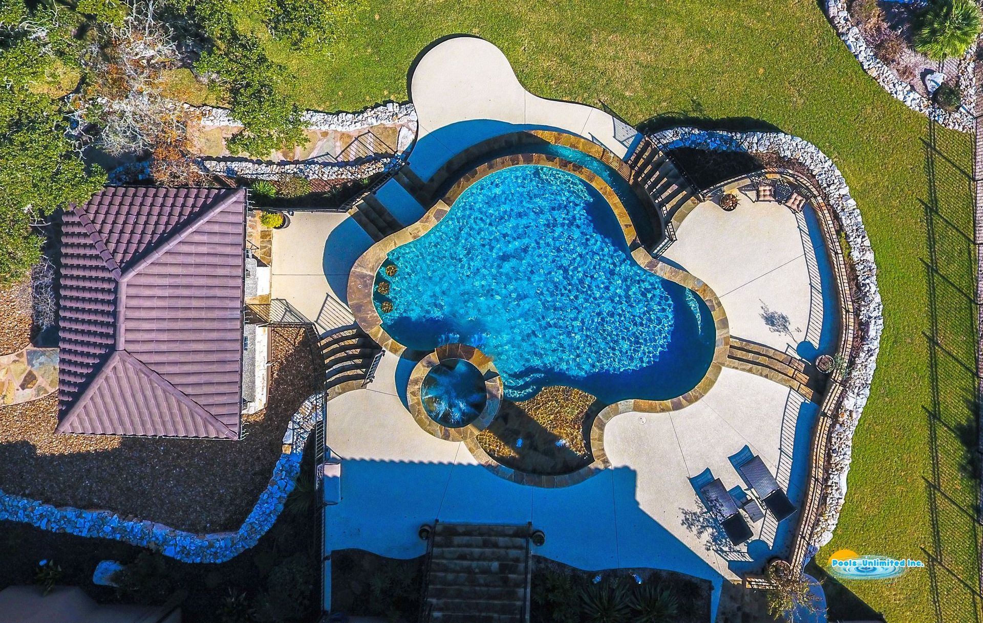 An aerial view of a swimming pool in the backyard of a house.