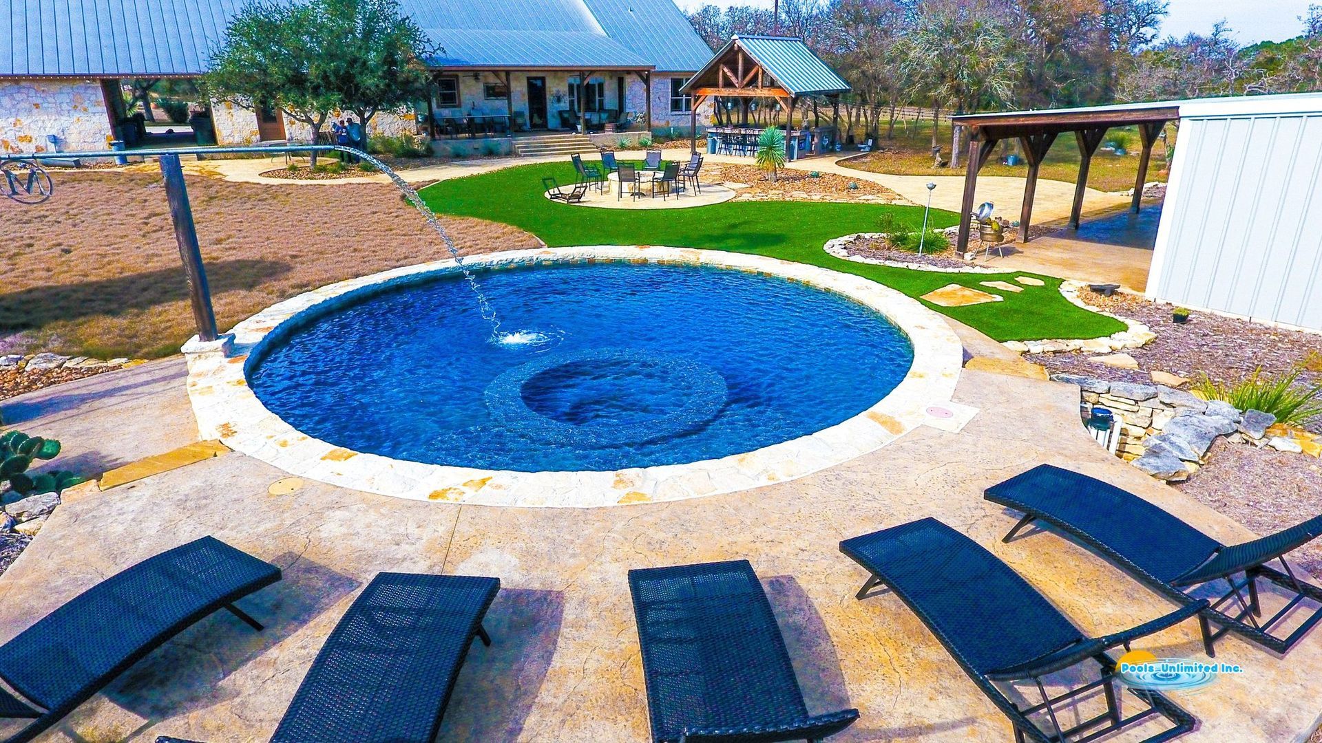 An aerial view of a large swimming pool in front of a large house.