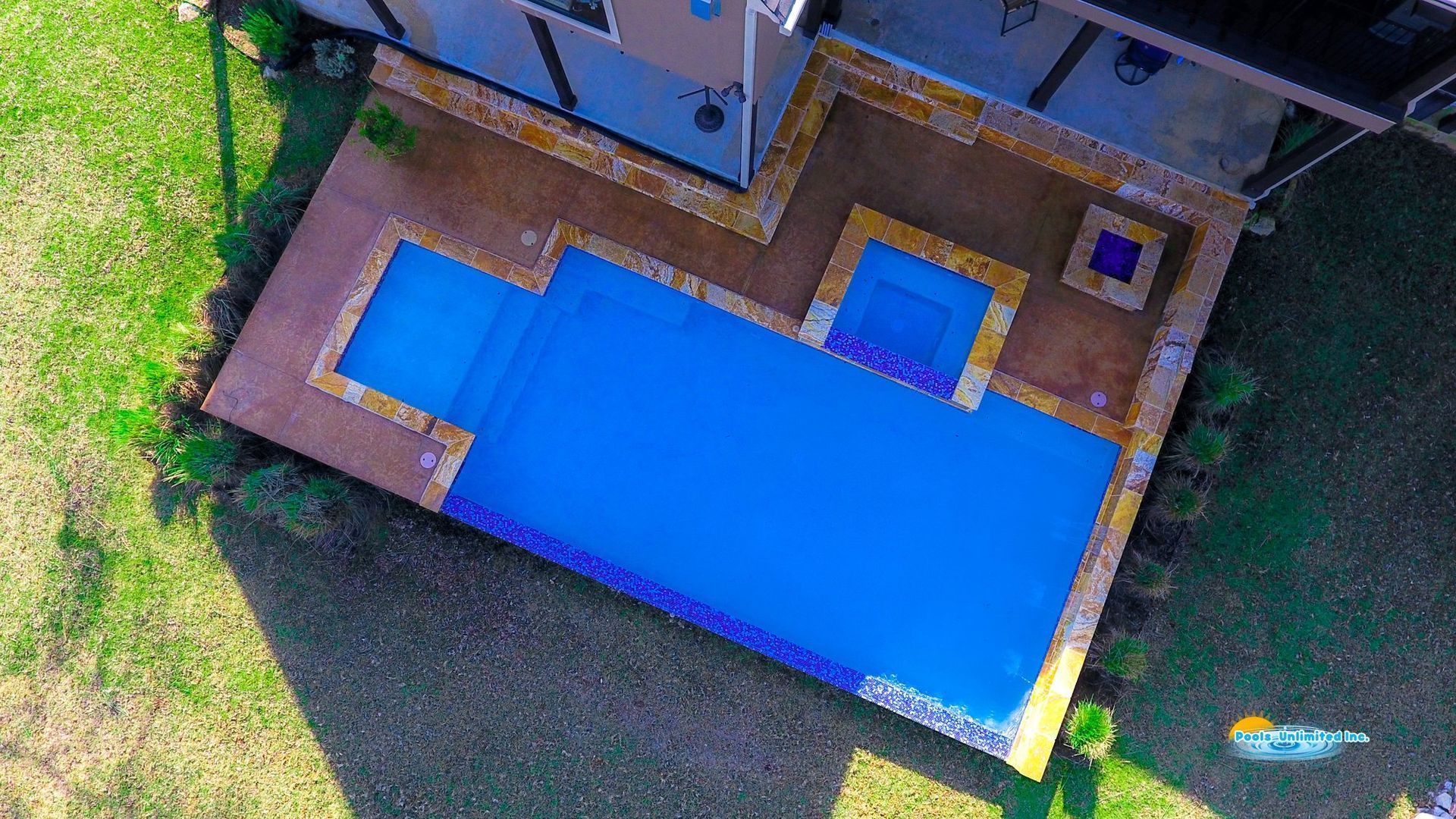 An aerial view of a large house with a large pool in the backyard.