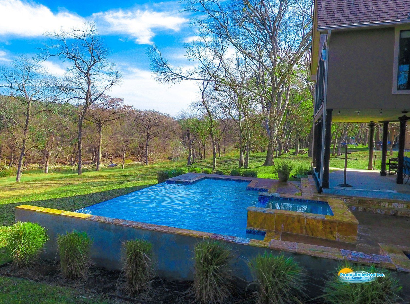 There is a large swimming pool in the backyard of a house.