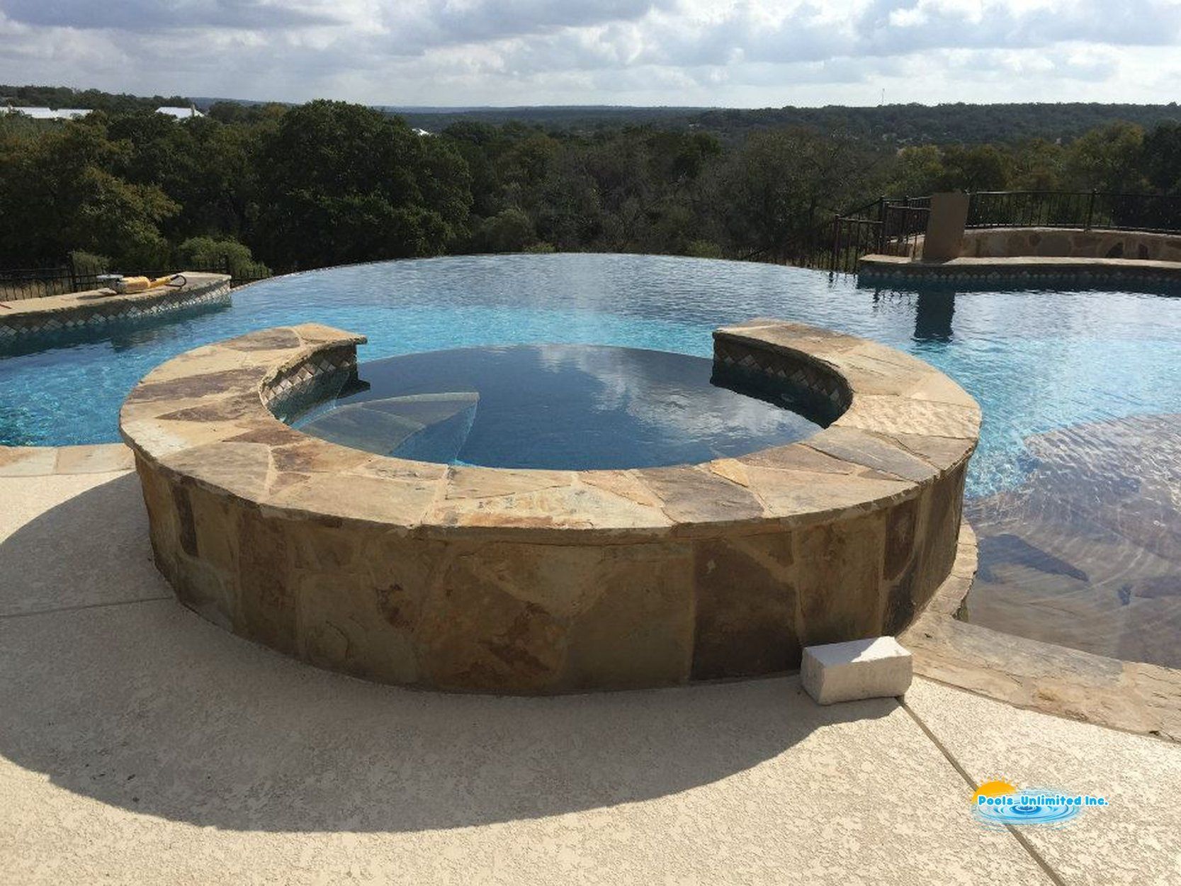 A large swimming pool with a hot tub in the backyard of a house.