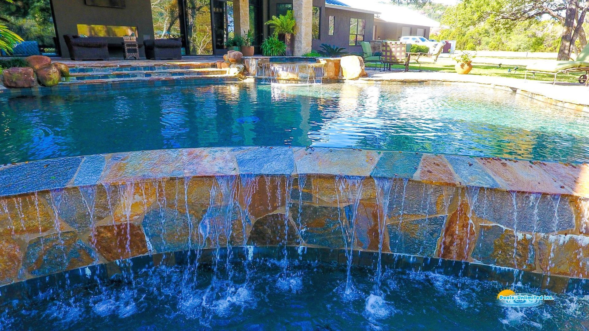 A large swimming pool with a waterfall and a diving board