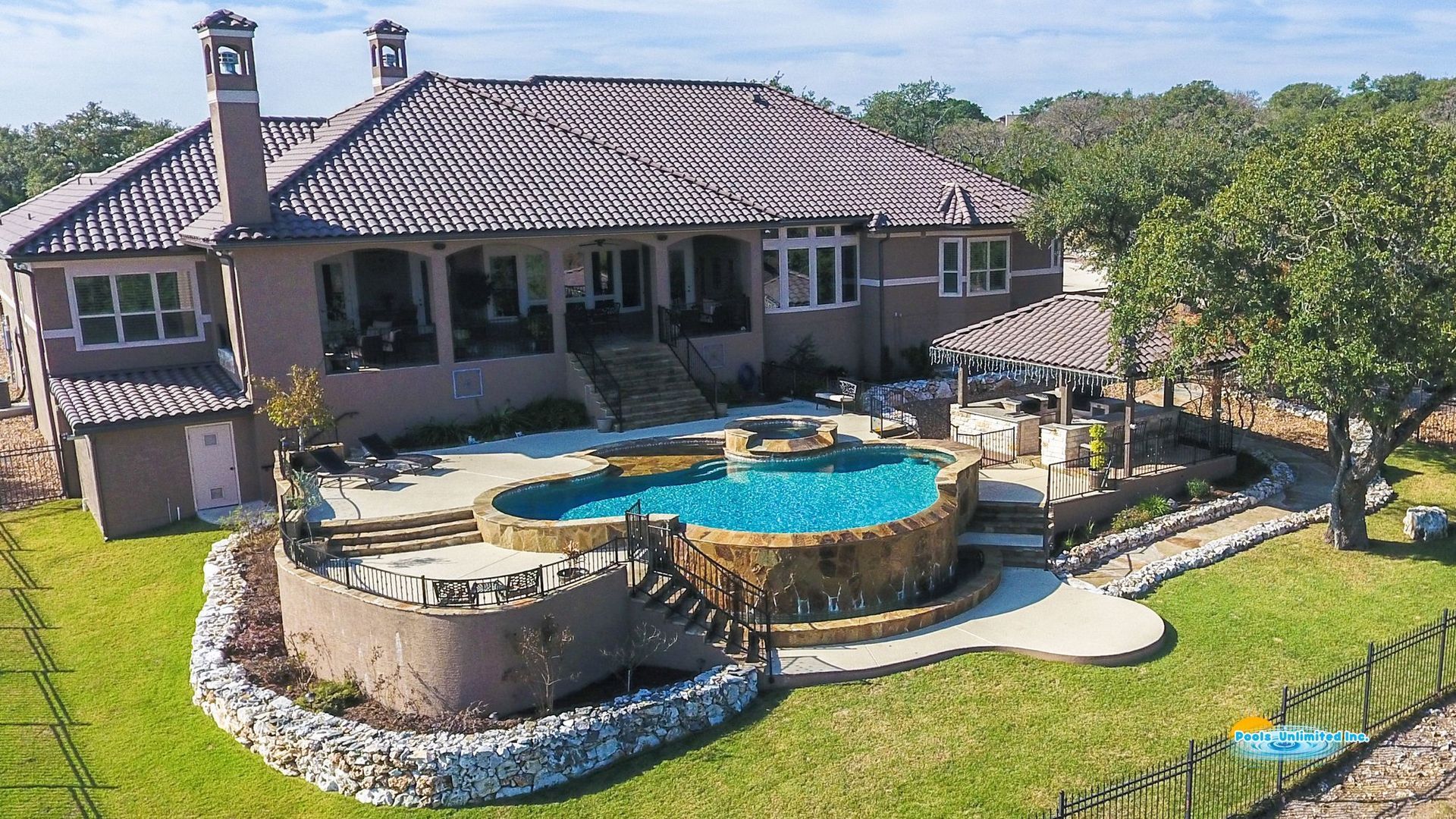 An aerial view of a large swimming pool in the backyard of a house.
