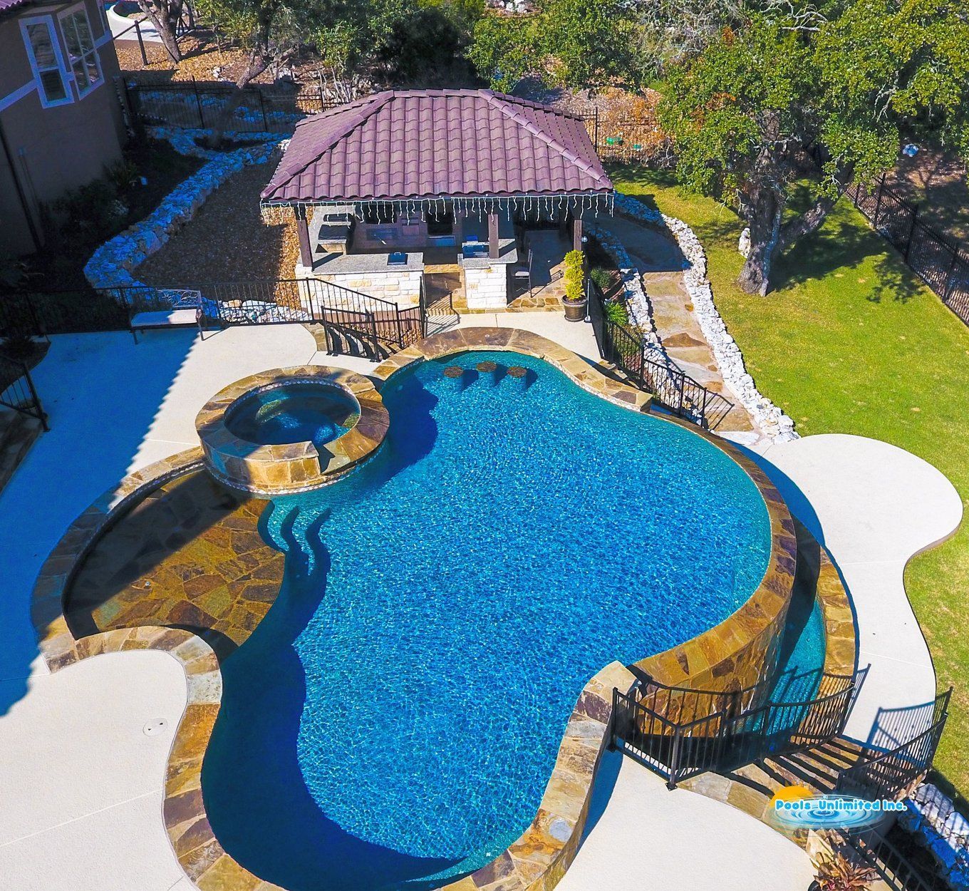 There is a large swimming pool in the backyard of a house.