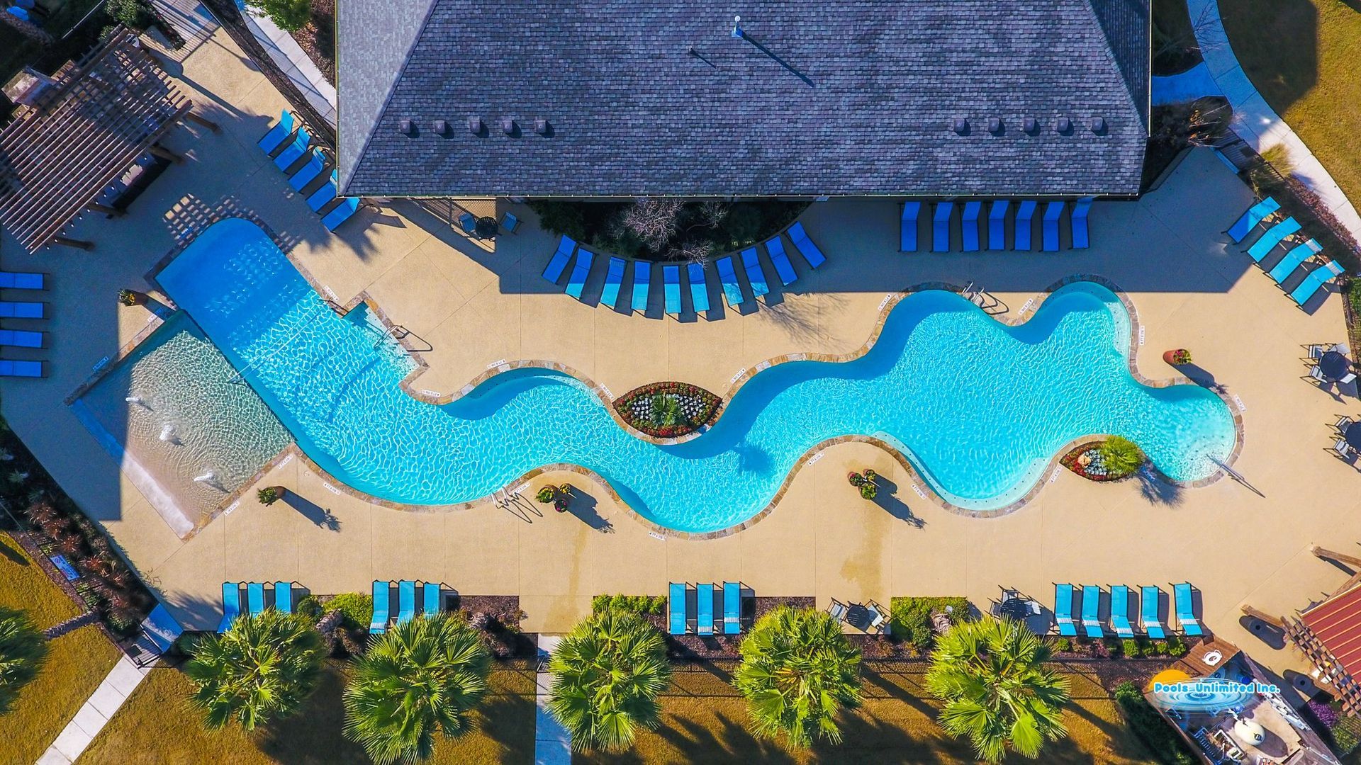 An aerial view of a large swimming pool surrounded by chairs and trees.