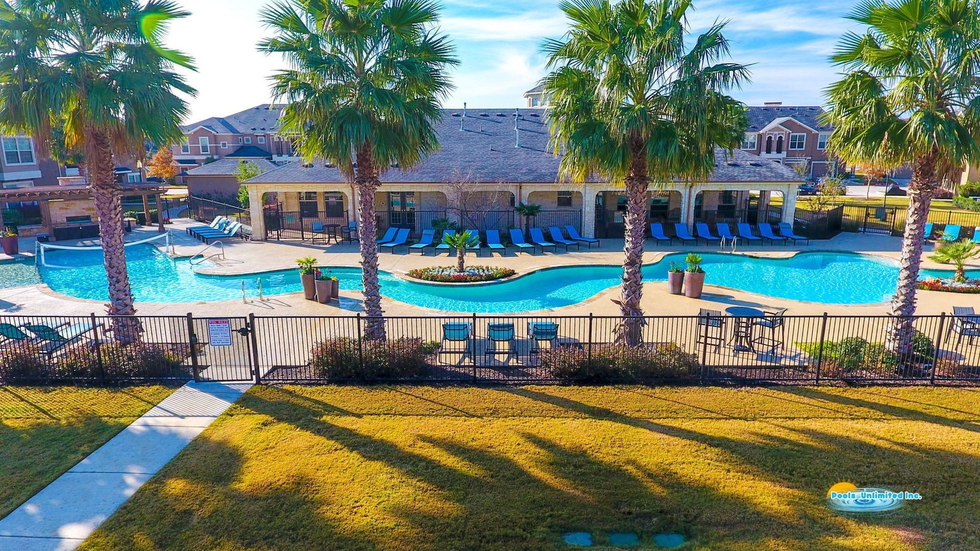 An aerial view of a large swimming pool surrounded by palm trees.