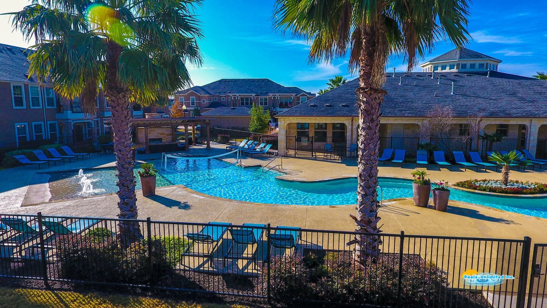 An aerial view of a large swimming pool surrounded by palm trees.