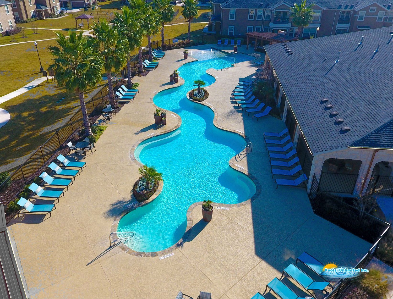 An aerial view of a large swimming pool surrounded by chairs and palm trees.