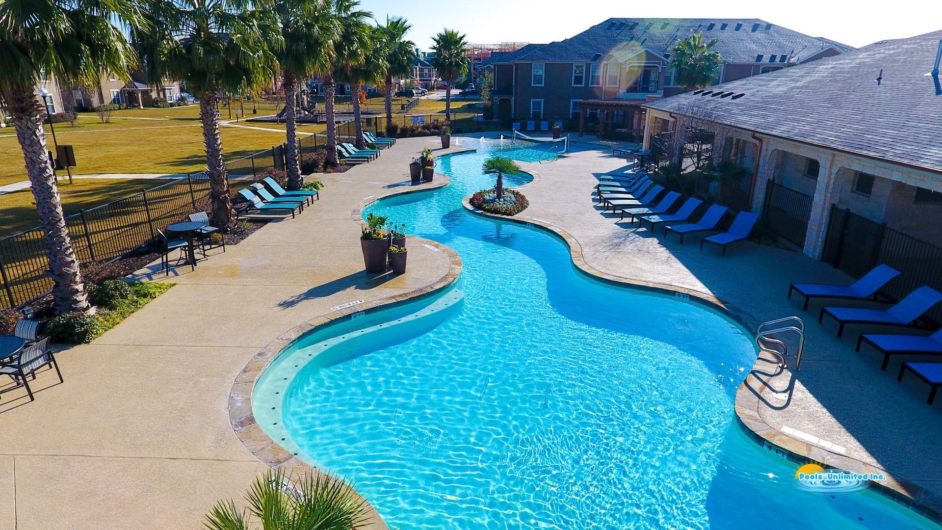 An aerial view of a large swimming pool surrounded by chairs and palm trees
