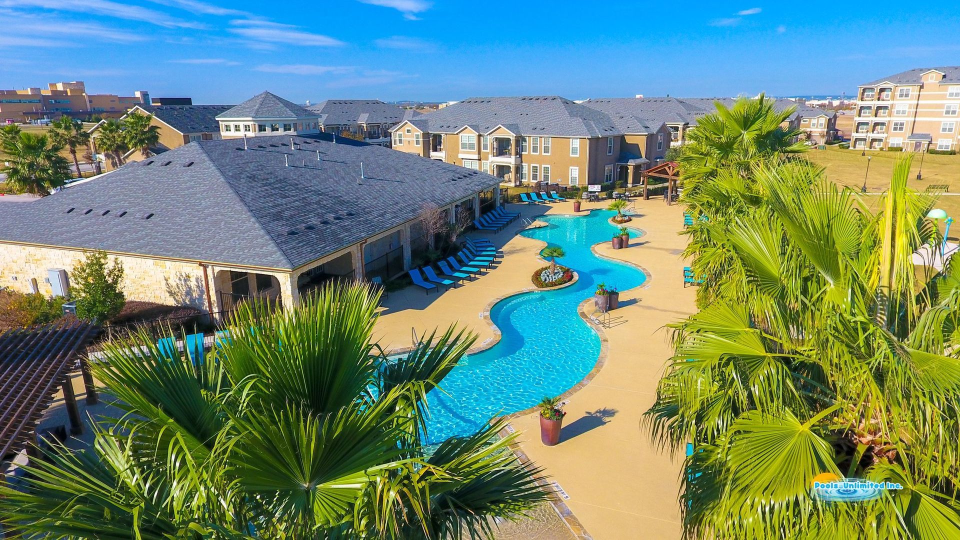 An aerial view of a large swimming pool surrounded by palm trees.