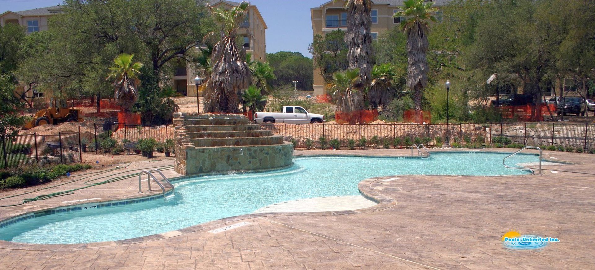 A white truck is parked in front of a large swimming pool