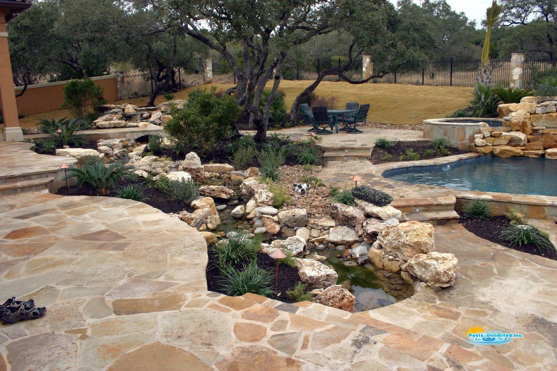 A backyard with a swimming pool surrounded by rocks and trees