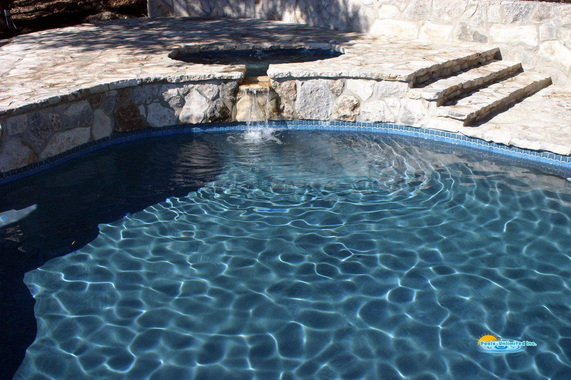 A swimming pool with a fountain in the middle of it