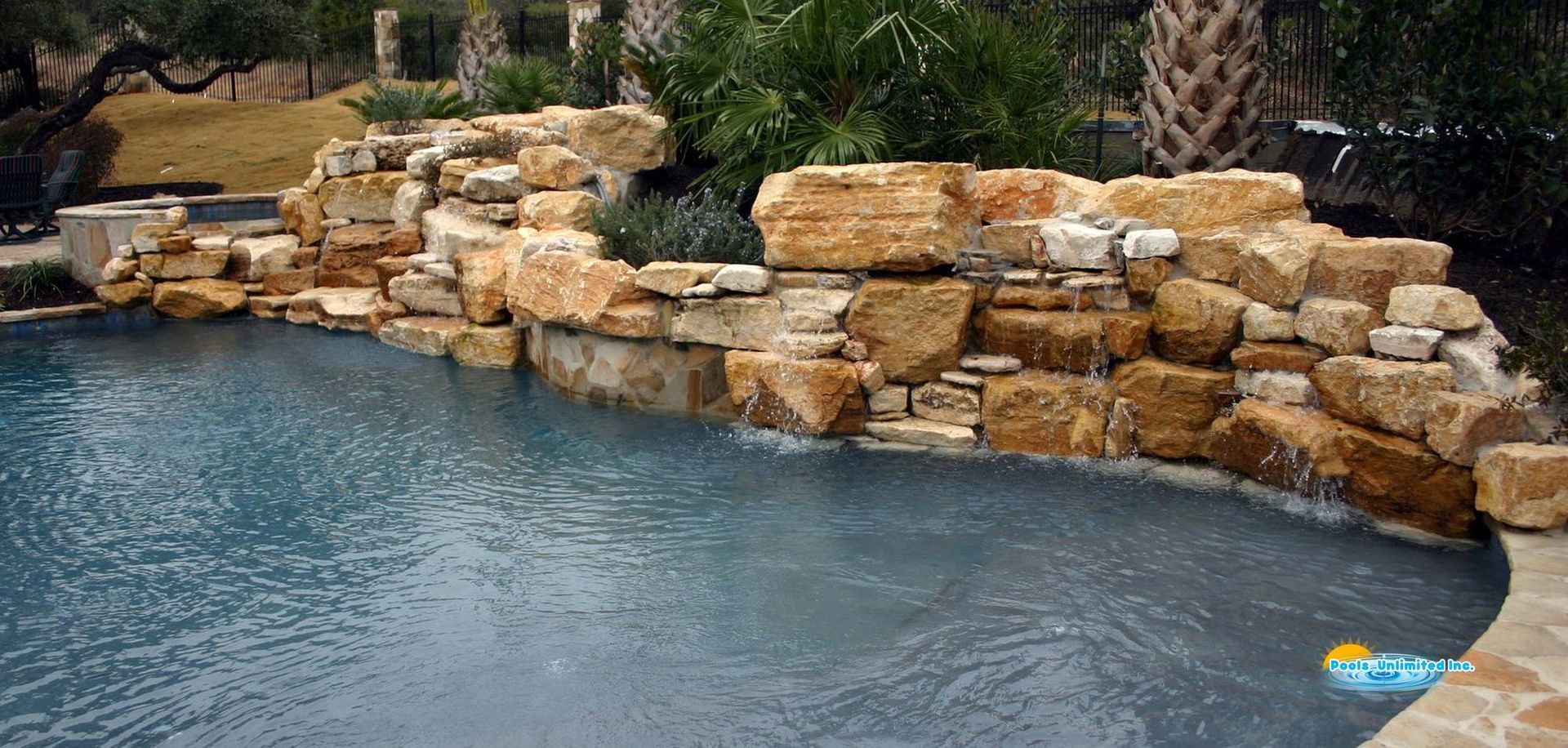 A large swimming pool surrounded by rocks and trees