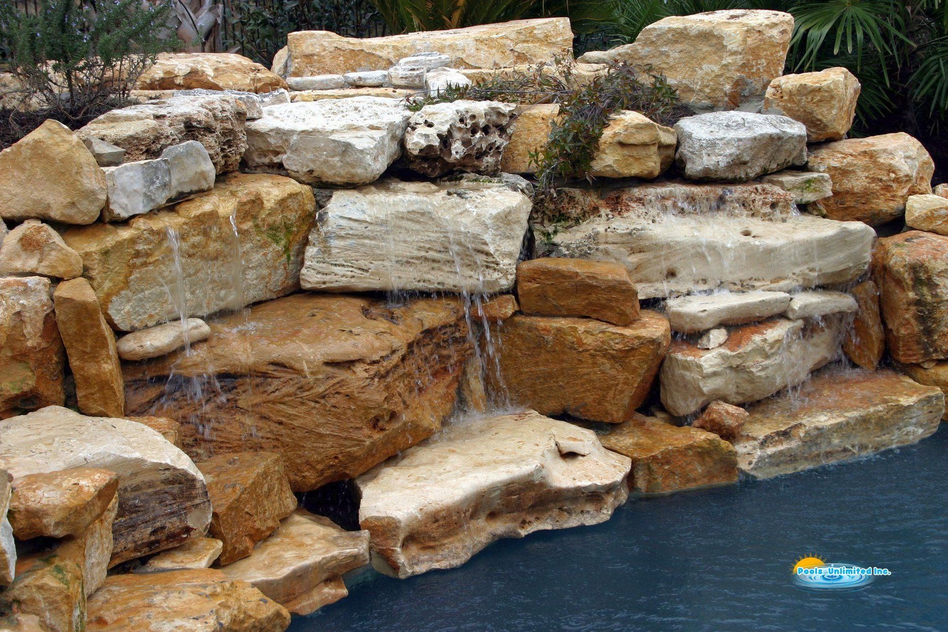 There is a waterfall in the middle of a pile of rocks.
