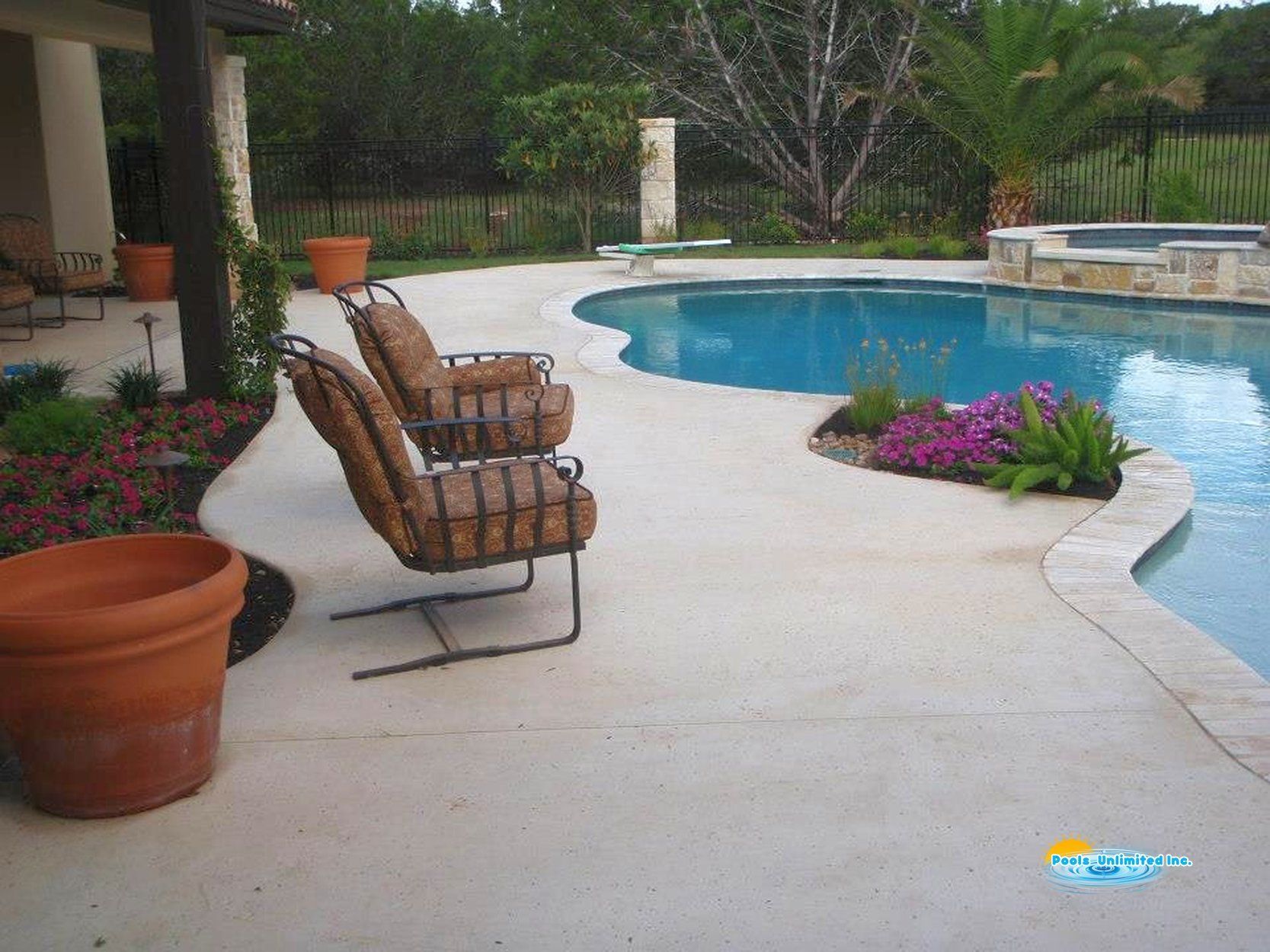 Two chairs are sitting on a patio next to a large swimming pool.