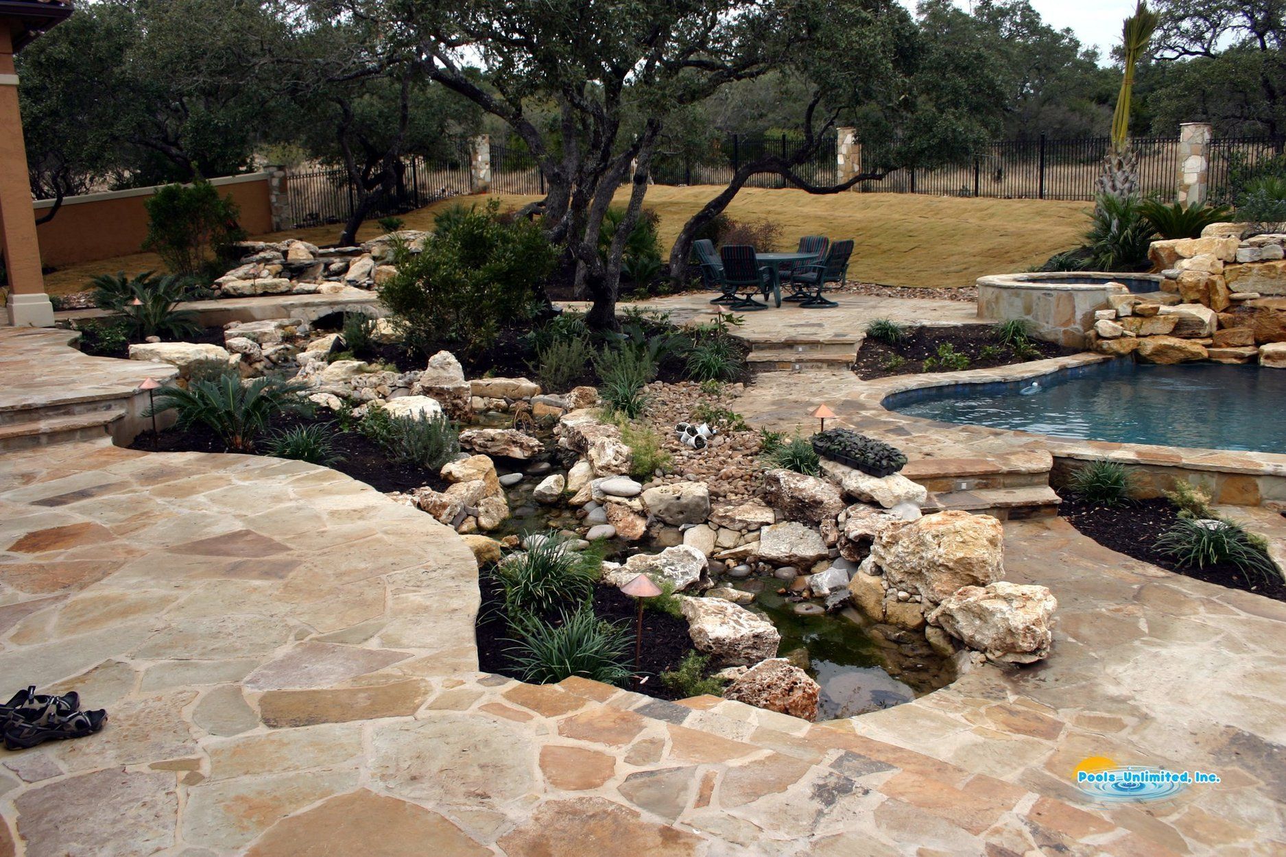 A backyard with a swimming pool surrounded by rocks and trees
