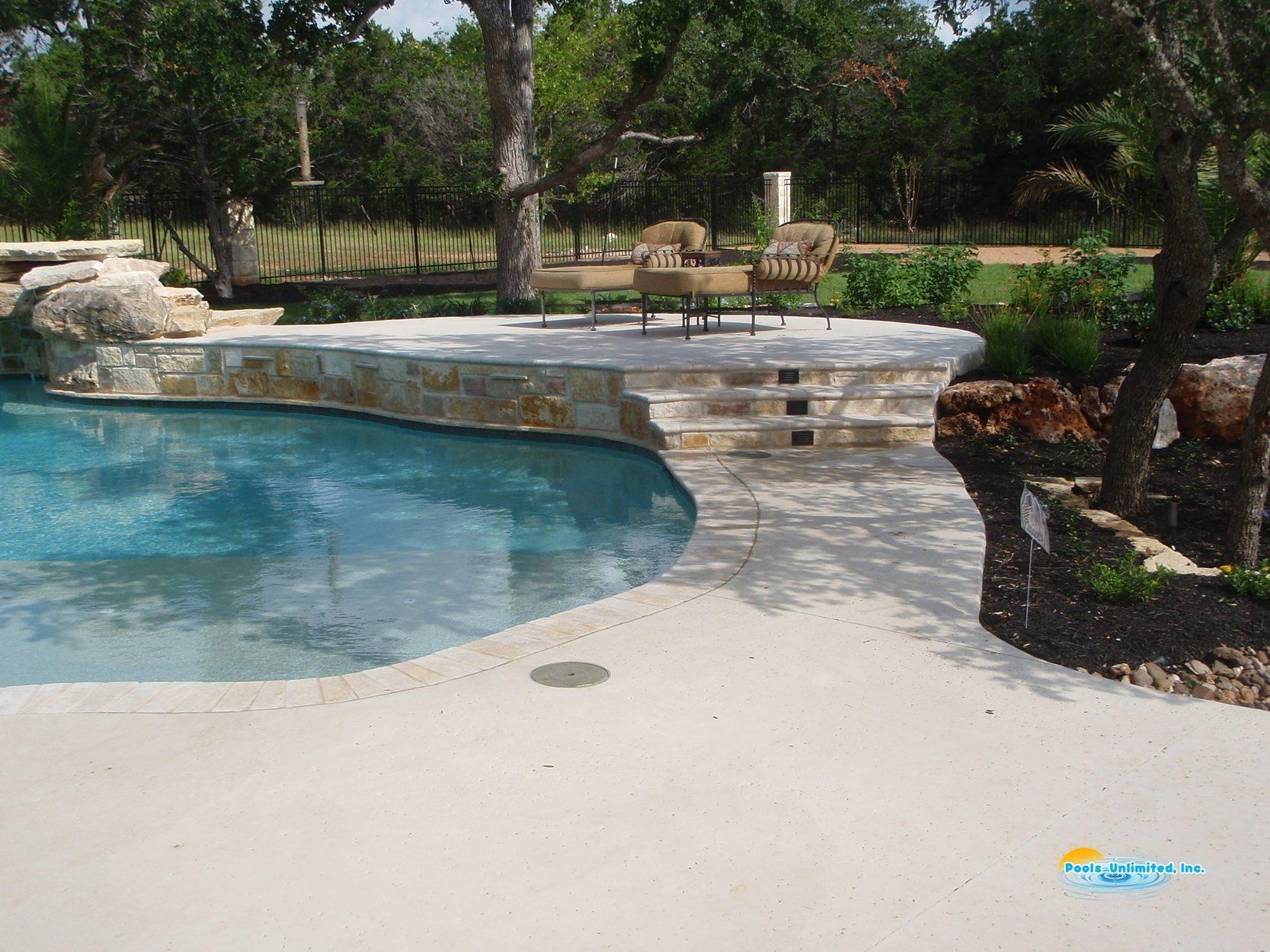 A large swimming pool is surrounded by chairs and trees