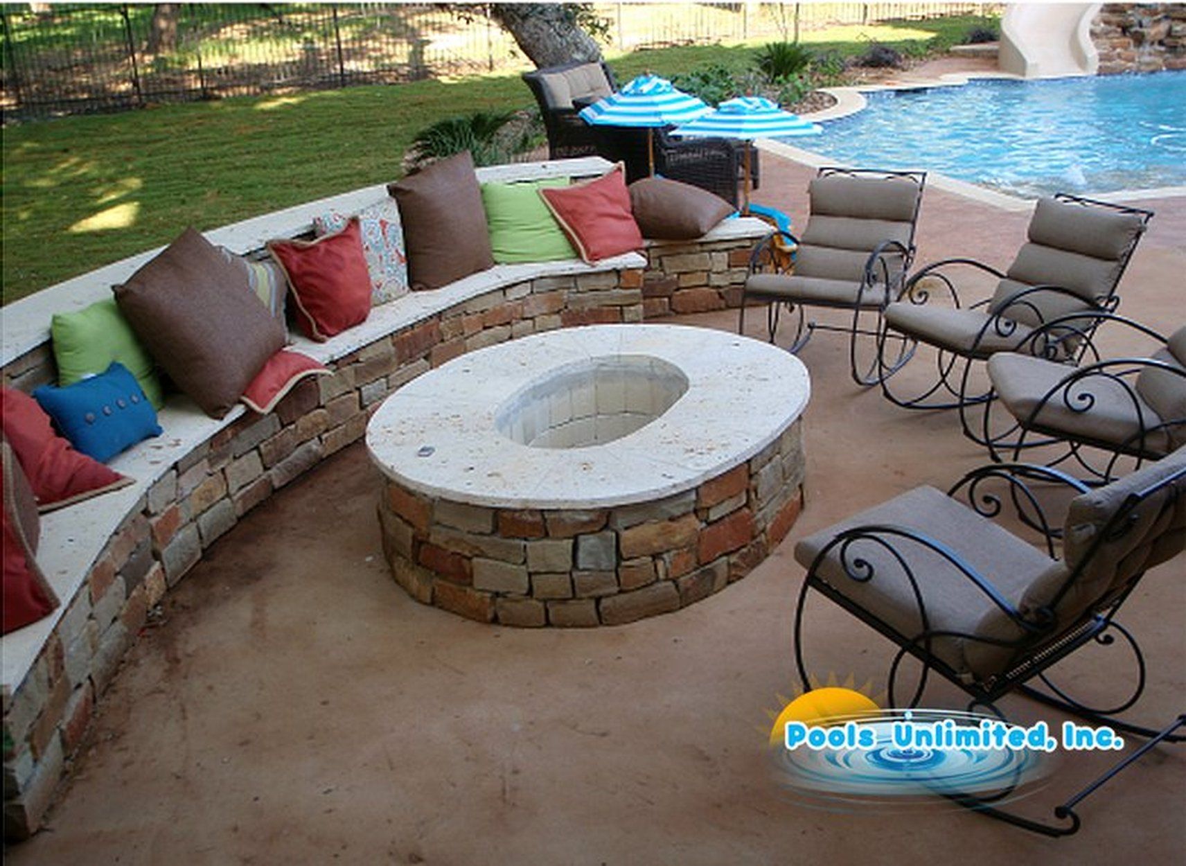 A fire pit sits in the middle of a patio next to a pool