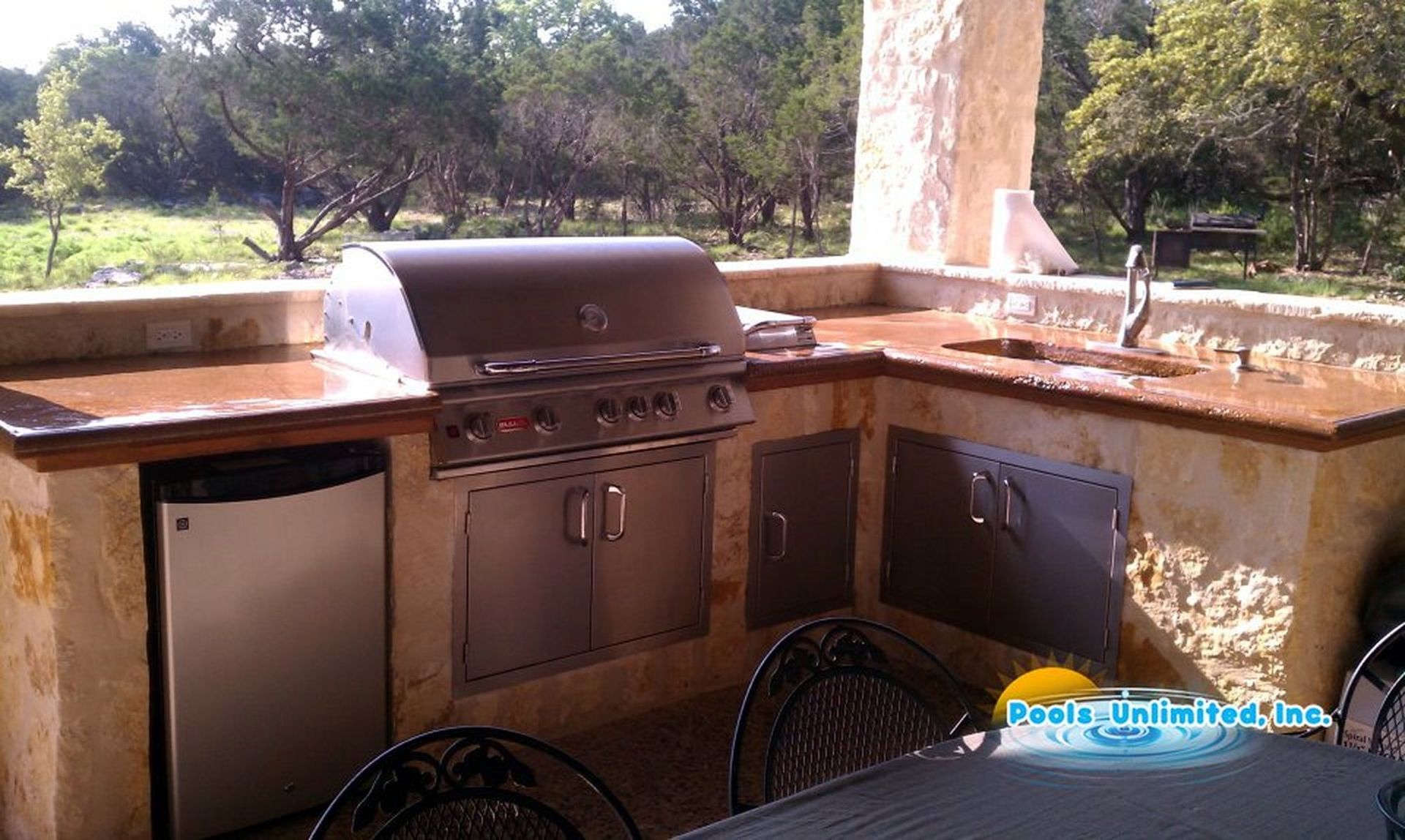 An outdoor kitchen with a grill , sink and dishwasher