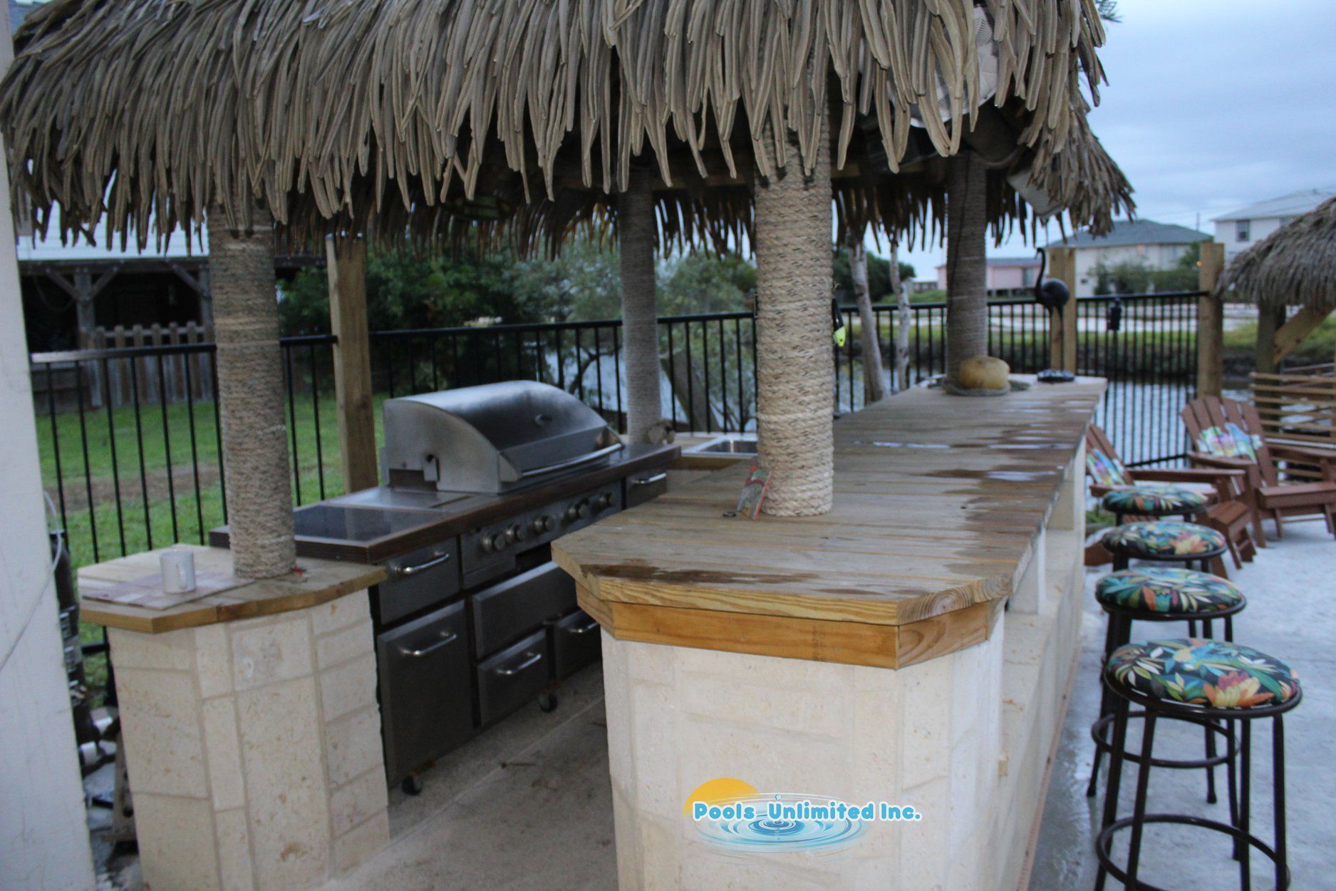 An outdoor kitchen with a thatched roof and a grill