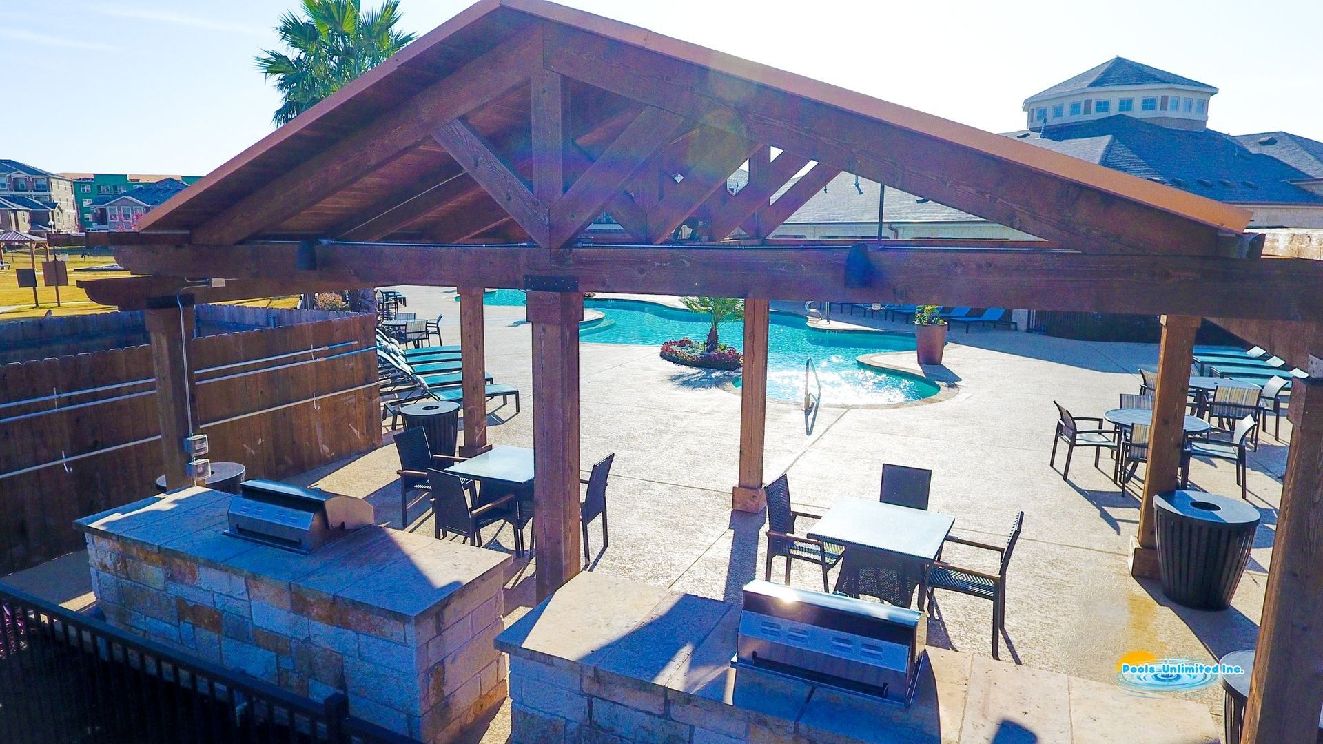 An aerial view of a patio area with tables and chairs under a wooden roof.