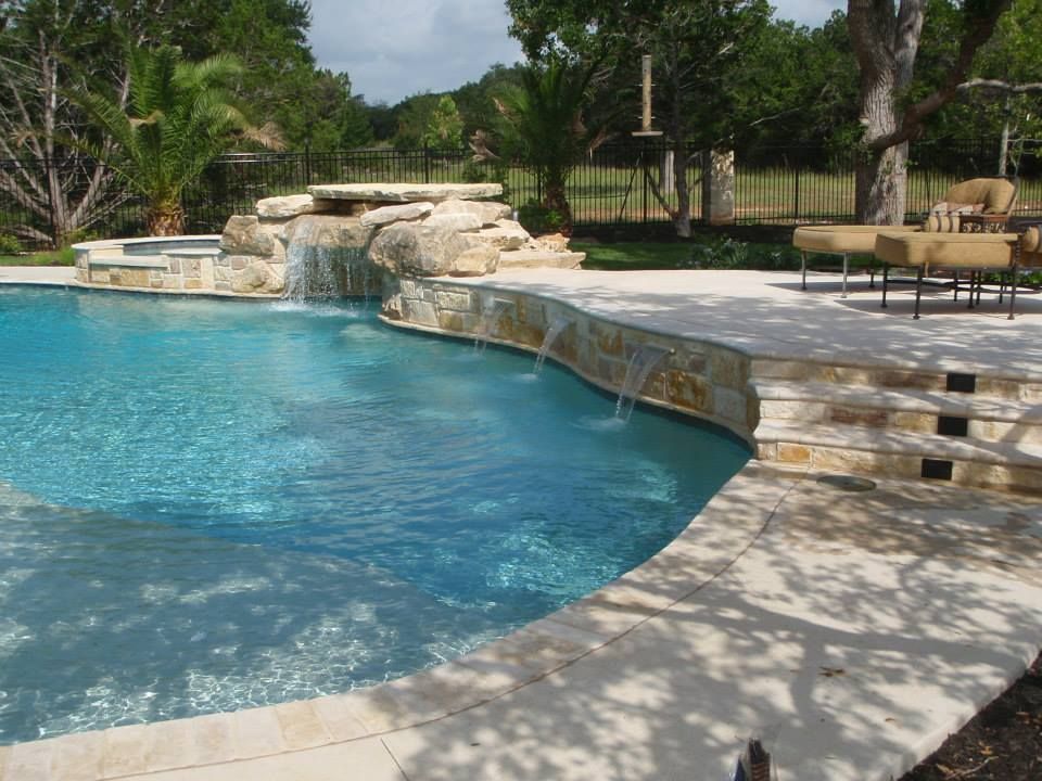 A large swimming pool with a waterfall in the middle