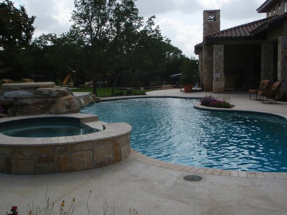 A large swimming pool with a hot tub in the middle