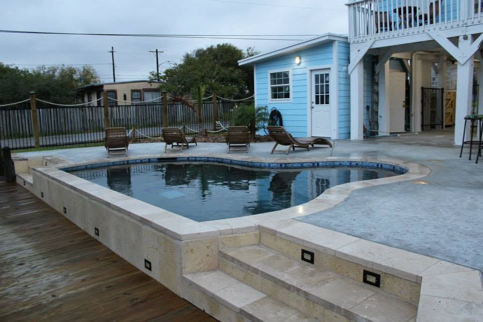 There is a large swimming pool in the backyard of a house.