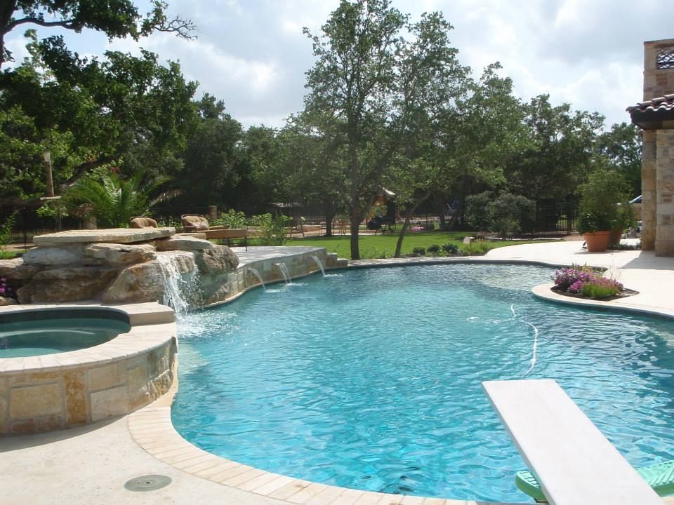 A large swimming pool with a waterfall and a hot tub