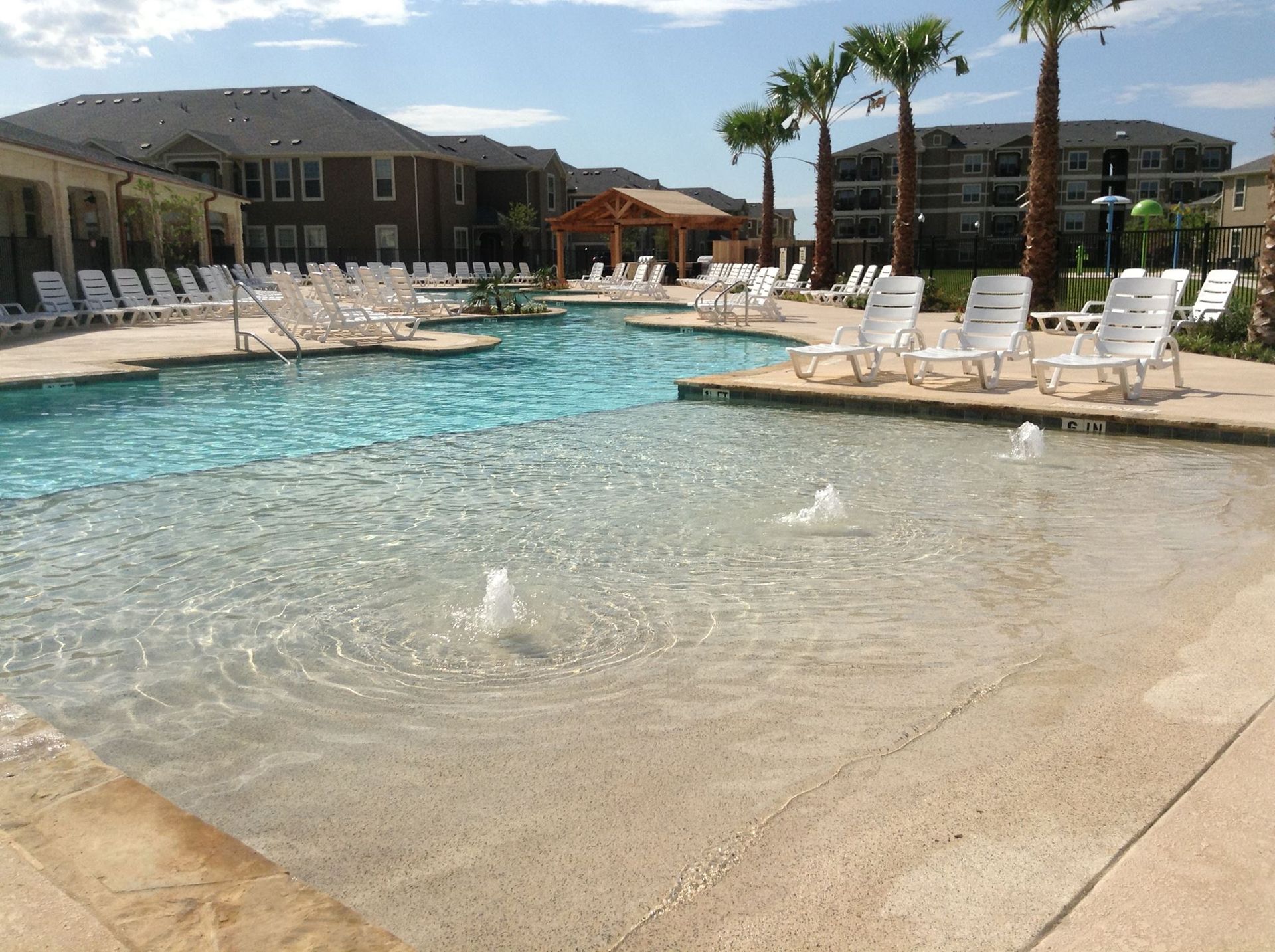 A large swimming pool surrounded by chairs and palm trees