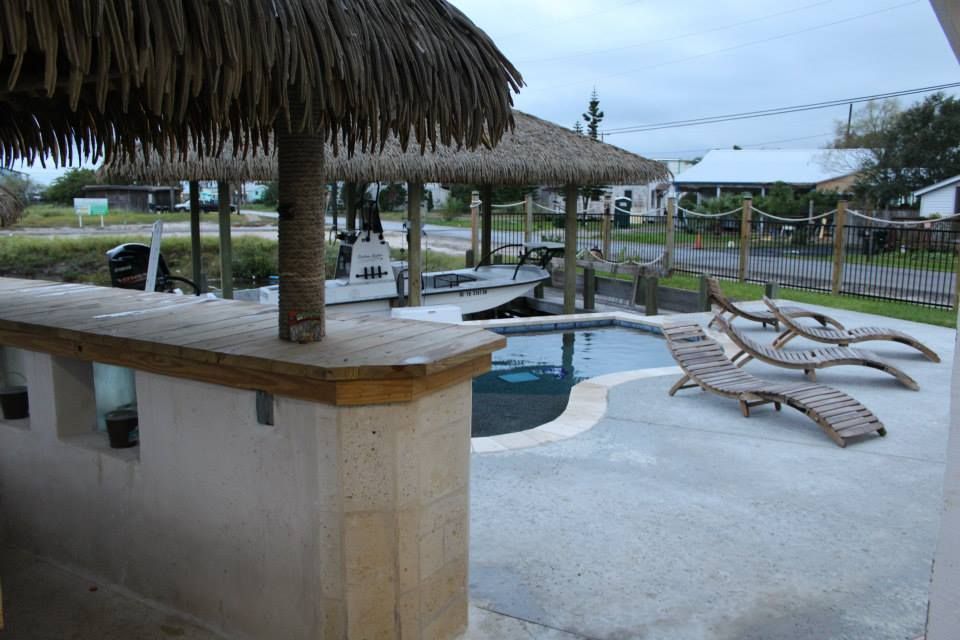 A patio with a thatched roof and a swimming pool