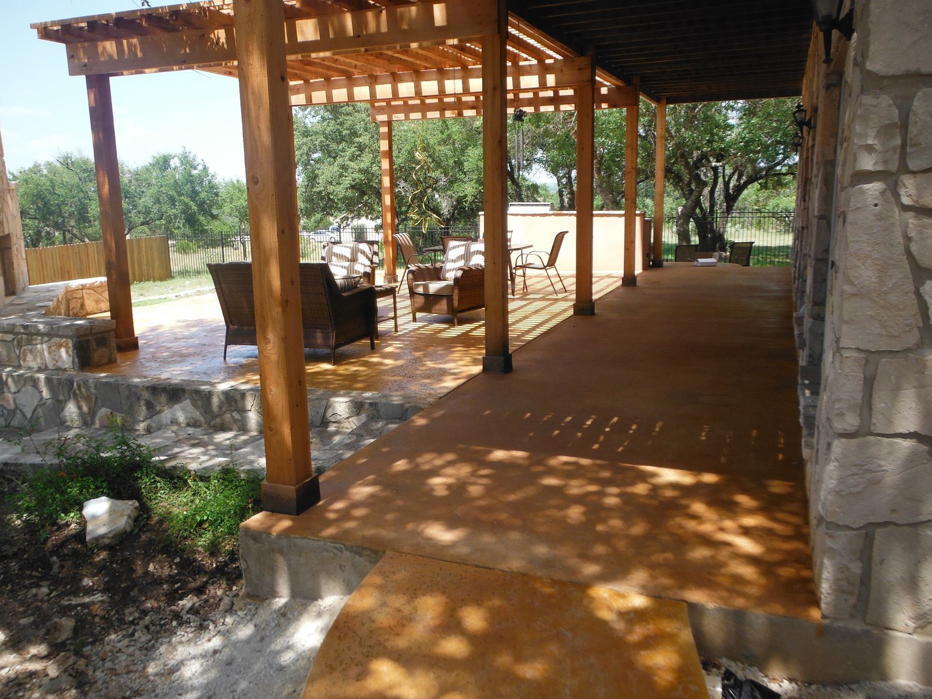 A patio with a wooden pergola and chairs