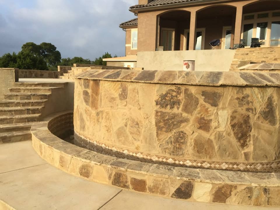 A large house with a stone wall and stairs in front of it