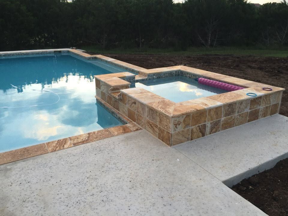 A swimming pool with a hot tub in the middle of it