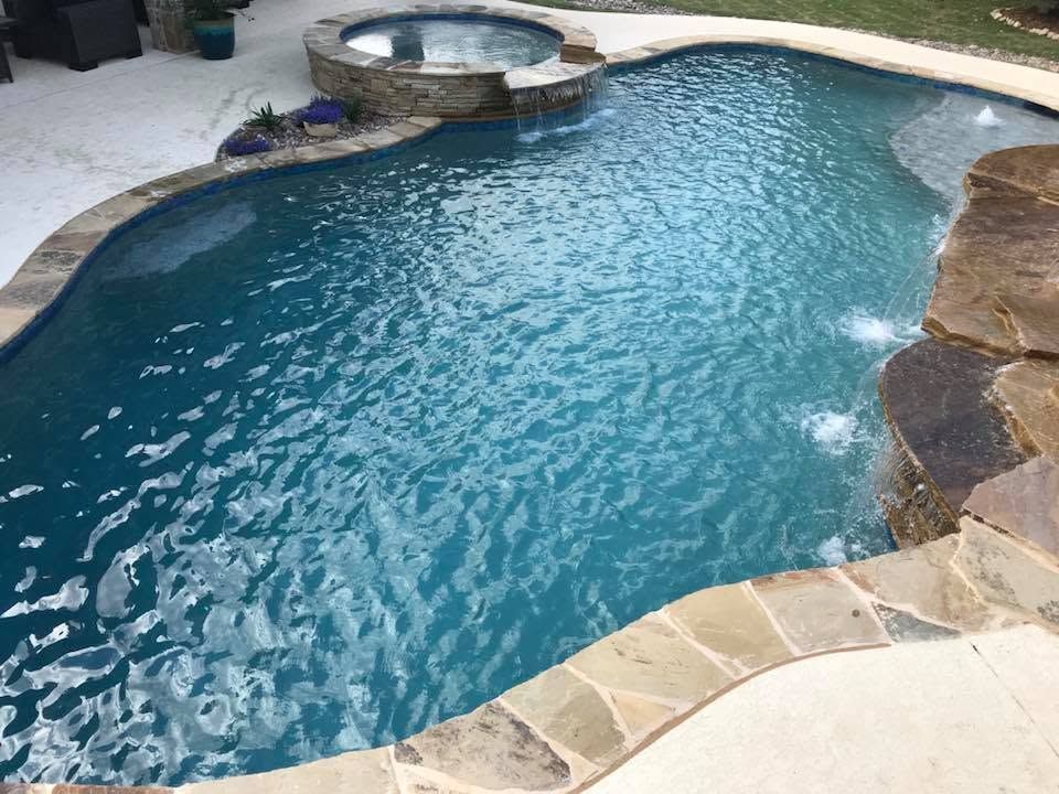 A large swimming pool with a hot tub in the middle of it.