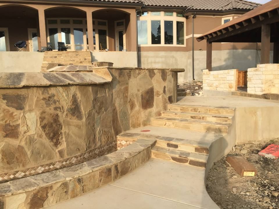 A house with a stone wall and stairs in front of it