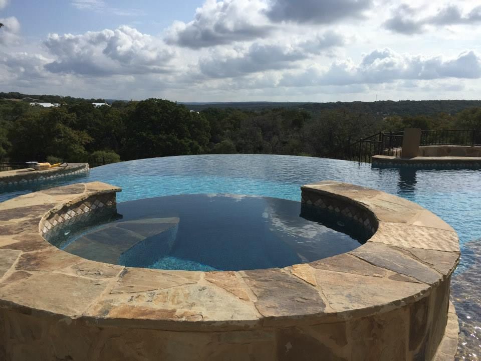 There is a swimming pool with a hot tub in the middle of it.