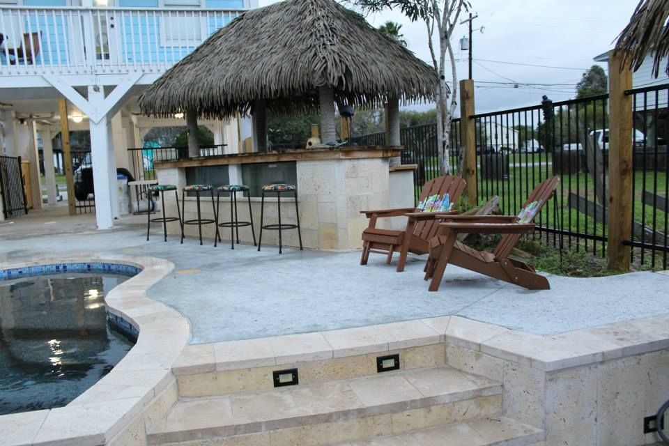 A patio with a thatched hut and a swimming pool