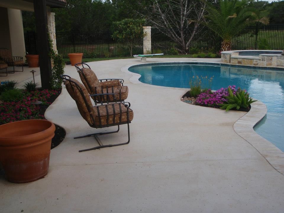Two chairs sit on a patio next to a large swimming pool