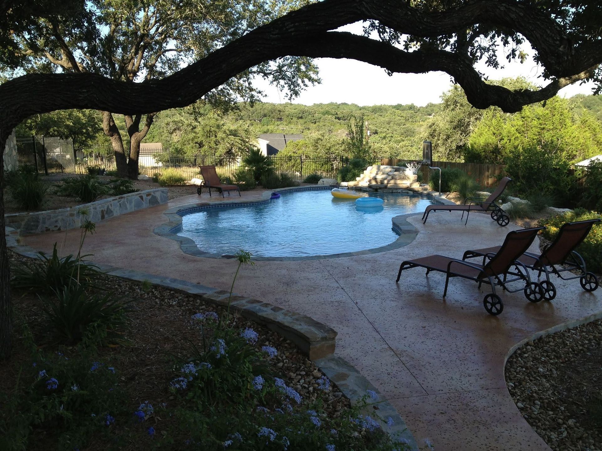 A large swimming pool is surrounded by chairs and trees
