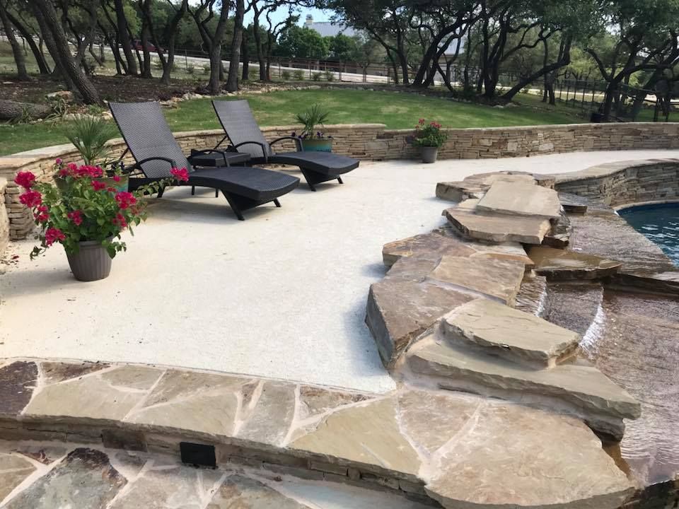 Two lounge chairs are sitting on a patio next to a pool.