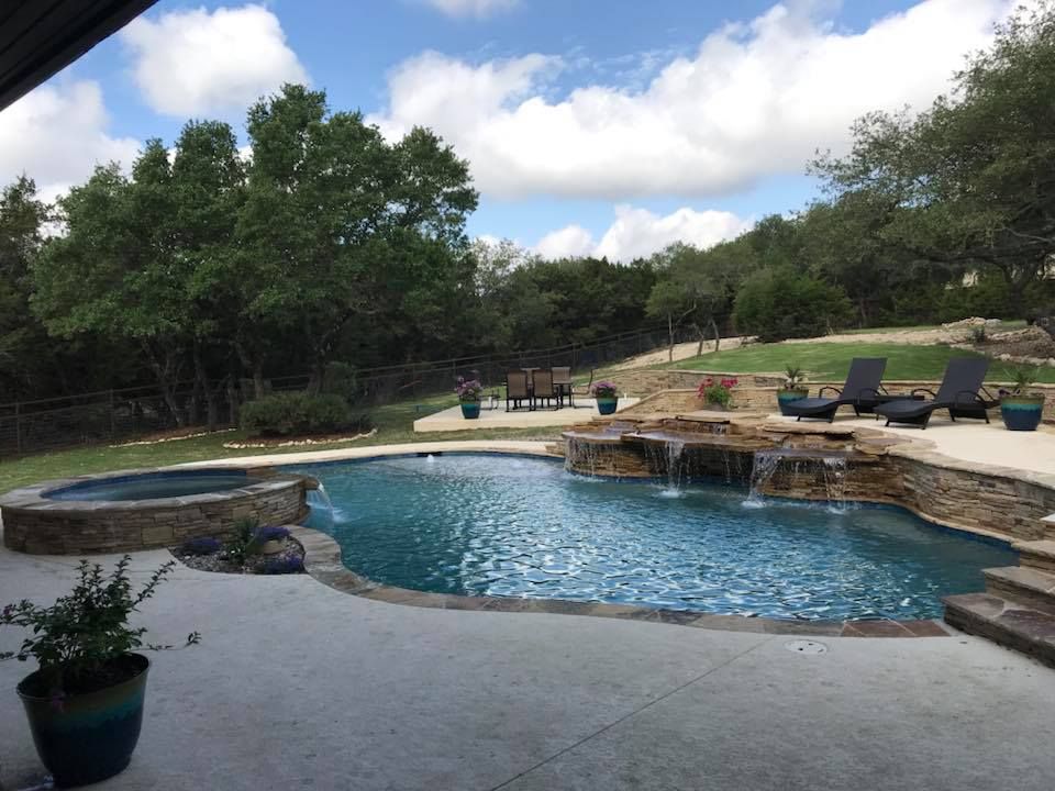 There is a large swimming pool with a waterfall in the backyard.