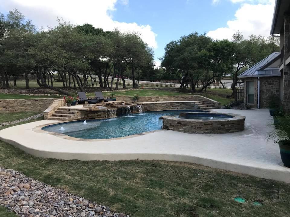 A large swimming pool with a hot tub in the backyard of a house.
