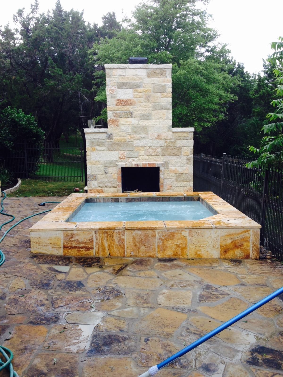 A stone fireplace with a hot tub in front of it.