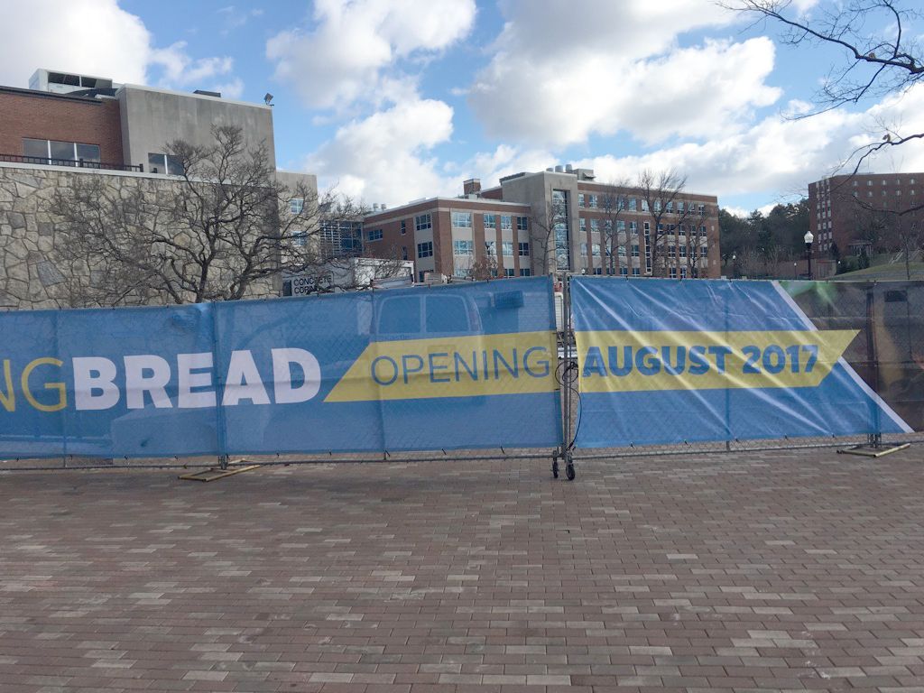 Blue and yellow banner on a construction fence: 