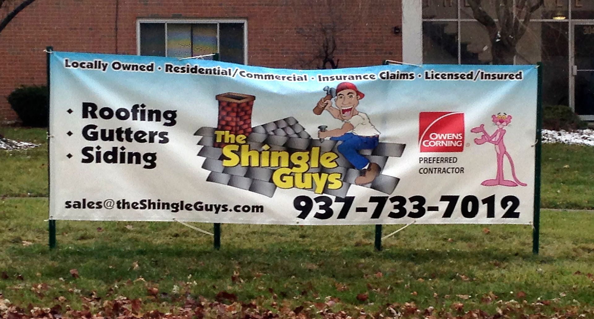 Banner for The Shingle Guys, roofing, gutters, siding services, including a cartoon worker and Pink Panther.