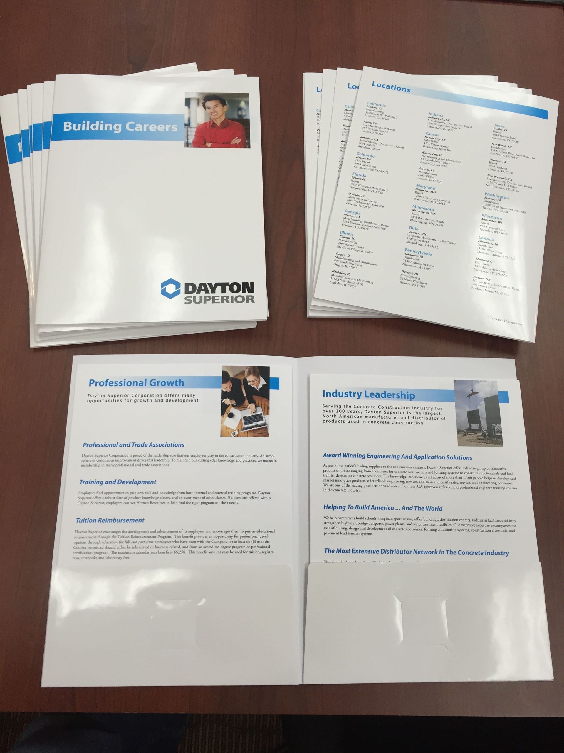 Stacks of Dayton, OH company brochures and documents on a brown table.