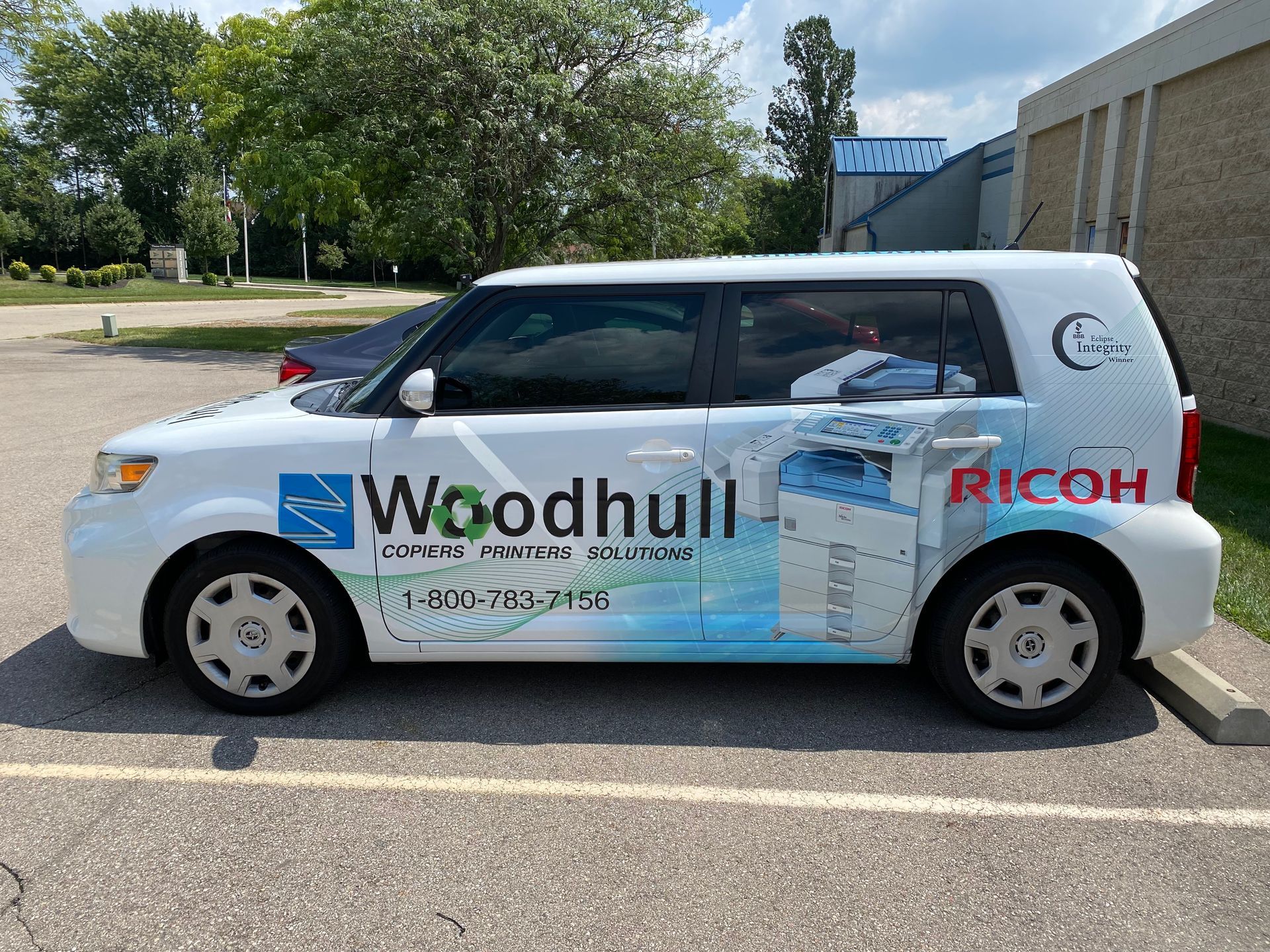 White car with company logo, parked in a parking lot.
