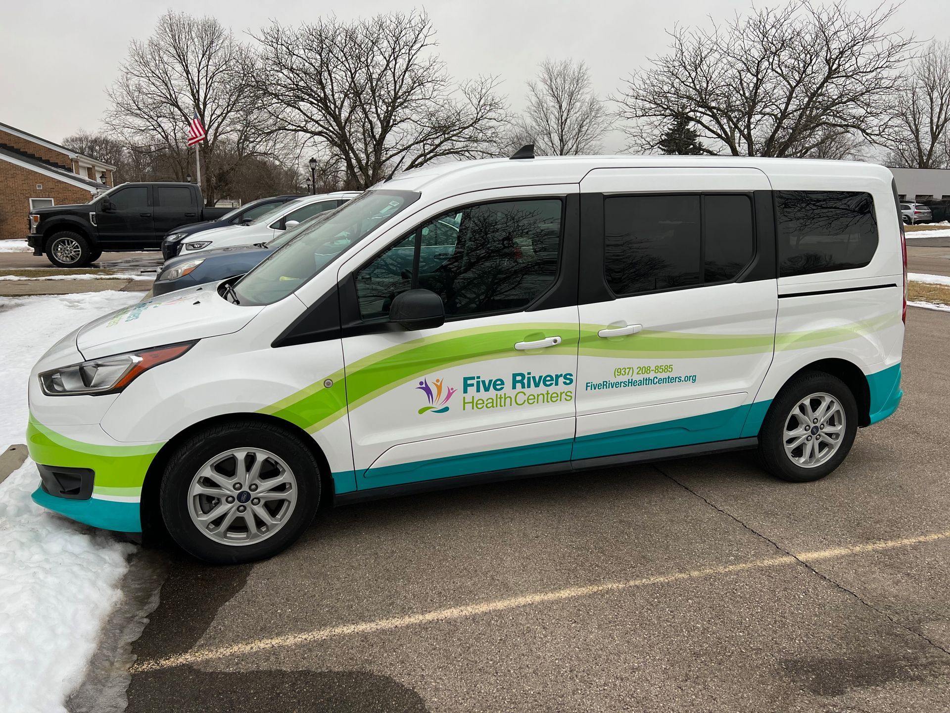 White van with green and teal logo parked in a lot with snow.